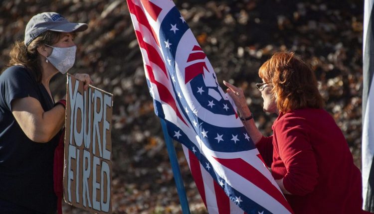 there two womans talking each other and hold board and flag